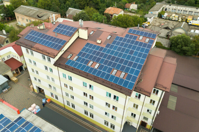 Aerial view of solar power plant with blue photovoltaic panels mounted of apartment building roof.