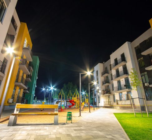 Yard between residential apartment buildings with empty wooden bench and modern flat housing. Real estate development.